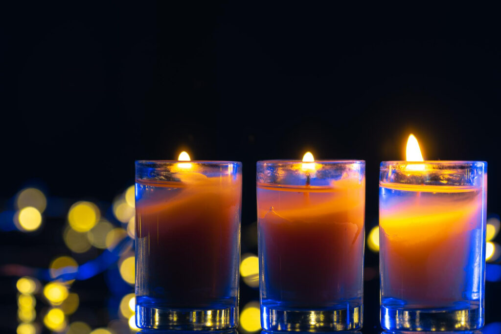 Imagem ilustrando o conteúdo sobre cores das velas mostrando três velas brancas sobre uma mesa em um ambiente escuro.