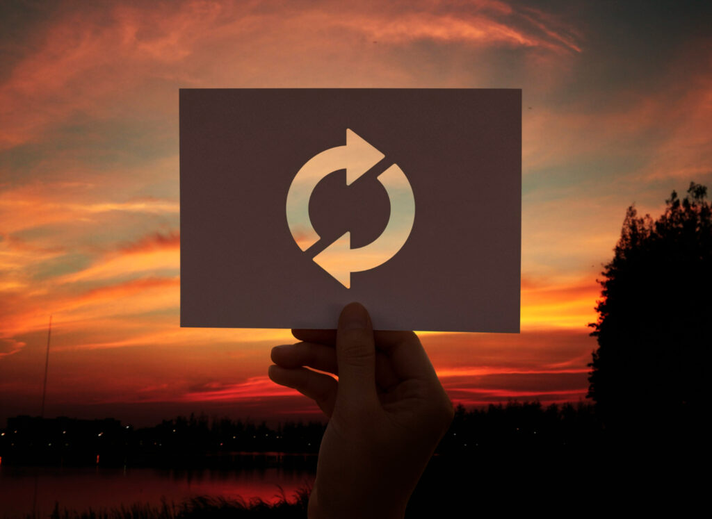 Imagem ilustrando o conteúdo sobre horas iguais e sincronicidade mostrando um ícone de repetição em um papel e, ao fundo, um por do sol.