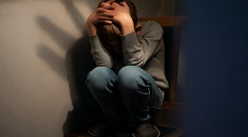 Imagem ilustratando o conteúdo sobre depressão e tristeza mostrando uam criança encolhida em uma cadeira.