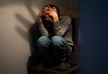 Imagem ilustratando o conteúdo sobre depressão e tristeza mostrando uam criança encolhida em uma cadeira.